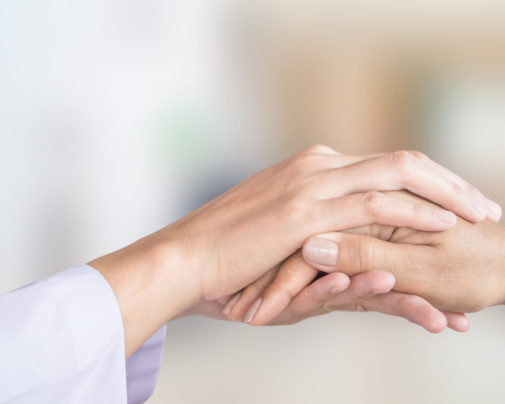 female doctor hand comforting patient with blur background of hospital room